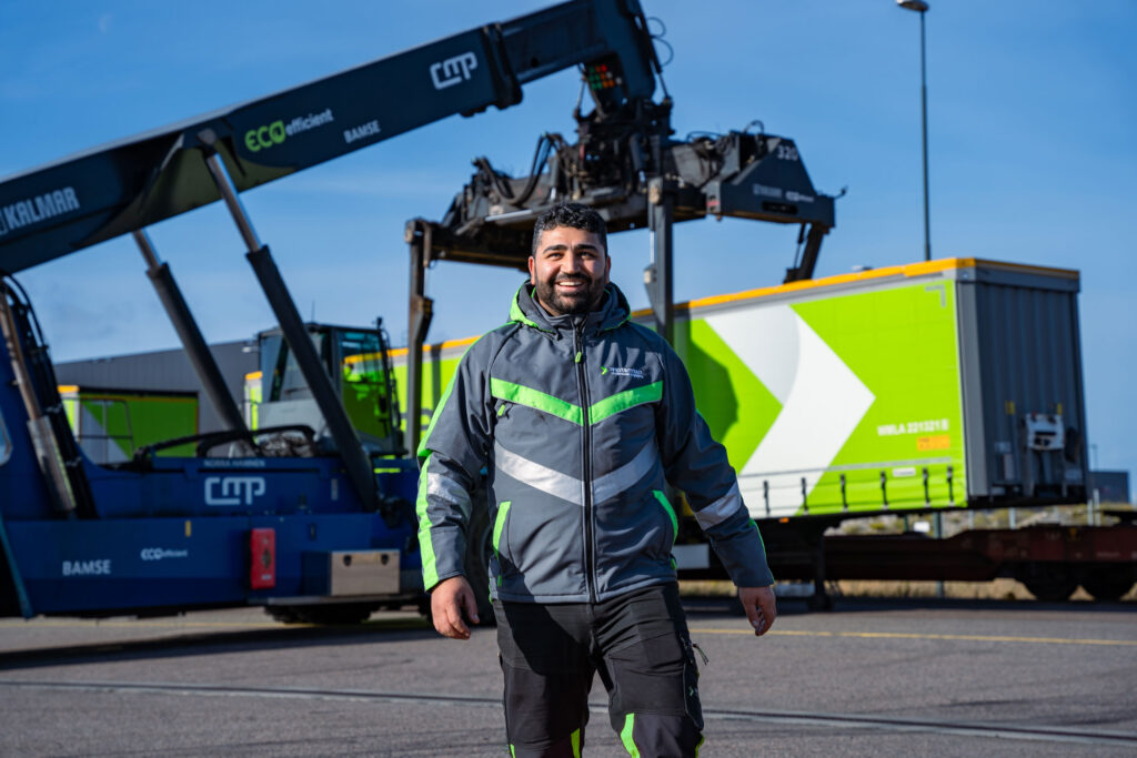 Medewerker loopt voor reachtruck die trailer optilt