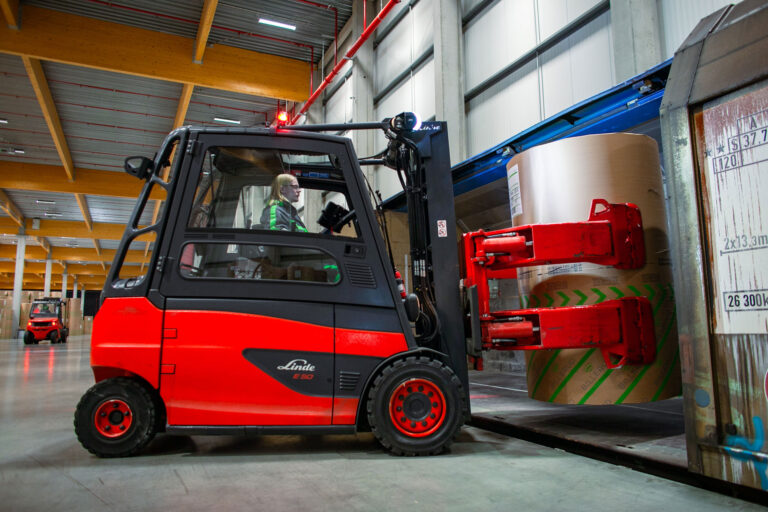 Rode heftruck zet papierrol in wagon