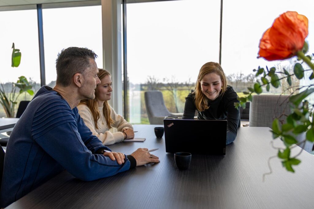 Overleg met drie personen rond laptop