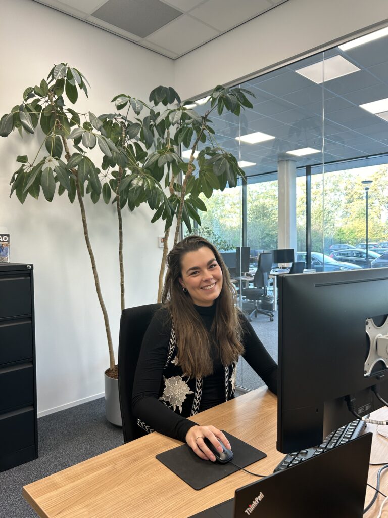 Medewerker werkt aan bureau met planten op achtergrond